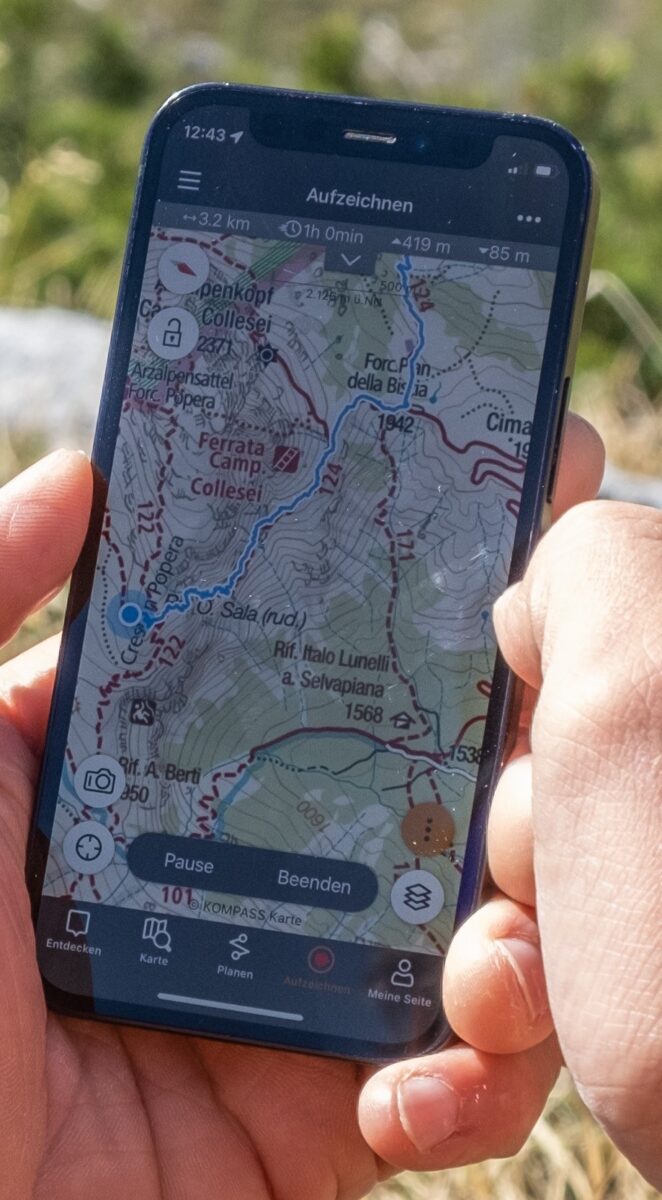 Eine Hand hält ein Smartphone mit der Alpenvereinaktiv-App; auf dem Bildschirm ist eine Wanderkarte mit aufgezeichneter Route zu sehen.